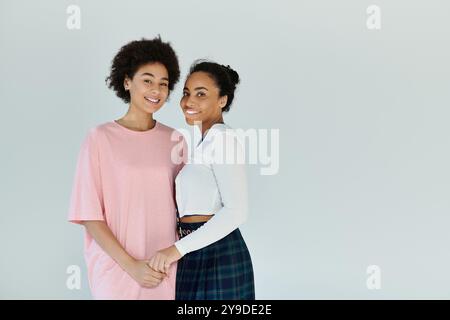 Zwei lächelnde junge Frauen stehen Seite an Seite, strahlen Freundschaft und Wärme in einem hellen Raum aus. Stockfoto