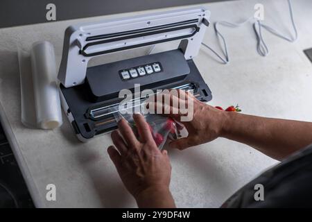 Die Hand eines Mannes benutzt eine Vakuummaschine, um Erdbeeren in Plastiktüten zu saugen. . Hochwertige Fotos Stockfoto