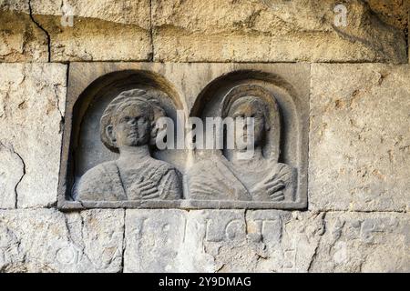 Das Detail des Grabes „Gemino Sepulchre“, das auf sechs verschiedene Freigelassene der Familien Clodia, Marcia und Annia Bezug nimmt und auf den Anfang des 1. Jahrhunderts v. Chr. datiert ist, besteht aus zwei Zellen, die über kleine Türen zugänglich sind, die sich nach außen auf eine Fassade öffnen, die von einem Tufffuß mit Skulpturen von Verstorbenen gekennzeichnet ist. Republikanische Gräber an der Via Statilia – Rom, Italien Stockfoto