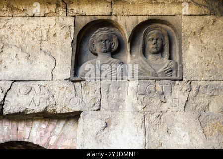 Das Detail des Grabes „Gemino Sepulchre“, das auf sechs verschiedene Freigelassene der Familien Clodia, Marcia und Annia Bezug nimmt und auf den Anfang des 1. Jahrhunderts v. Chr. datiert ist, besteht aus zwei Zellen, die über kleine Türen zugänglich sind, die sich nach außen auf eine Fassade öffnen, die von einem Tufffuß mit Skulpturen von Verstorbenen gekennzeichnet ist. Republikanische Gräber an der Via Statilia – Rom, Italien Stockfoto