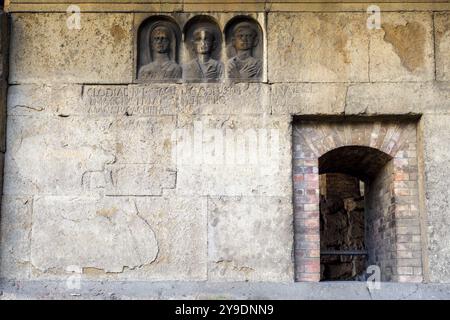 Das Detail des Grabes „Gemino Sepulchre“, das auf sechs verschiedene Freigelassene der Familien Clodia, Marcia und Annia Bezug nimmt und auf den Anfang des 1. Jahrhunderts v. Chr. datiert ist, besteht aus zwei Zellen, die über kleine Türen zugänglich sind, die sich nach außen auf eine Fassade öffnen, die von einem Tufffuß mit Skulpturen von Verstorbenen gekennzeichnet ist. Republikanische Gräber an der Via Statilia – Rom, Italien Stockfoto