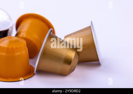 Kaffeekapseln in verschiedenen Farben sind auf einem schlichten weißen Hintergrund verteilt und bieten eine elegante und stilvolle Darstellung von Zubehör für die Kaffeezubereitung Stockfoto