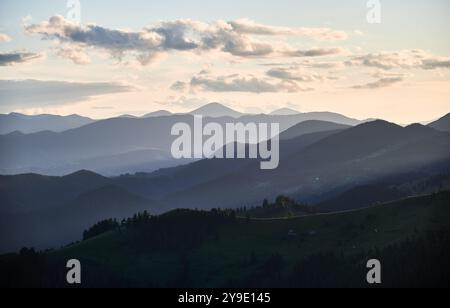 Die sanften Blautöne der mehrschichtigen Bergketten erstrecken sich bis in die Ferne unter dem Abendhimmel und schaffen eine ruhige und stimmungsvolle Landschaft mit sanften Steigungen und einem Gefühl von Weite. Stockfoto