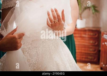 Eleganz im Detail: Ein Moment der Vorbereitung auf ein atemberaubendes Hochzeitskleid. Stockfoto