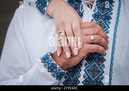 Ein elegantes Zeichen der Einheit: Nahaufnahme von ineinander verflochtenen Händen in traditioneller ukrainischer Stickerei. Stockfoto