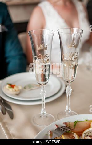 Elegantes Anstoßen auf die Hochzeit mit individuellen Champagnerflöten. Stockfoto