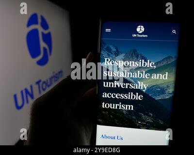 Person, die ein Smartphone hält, mit der Webseite der Organisation der Vereinten Nationen UN Tourismus auf dem Bildschirm vor dem Logo. Konzentrieren Sie sich auf die Mitte des Telefondisplays. Stockfoto