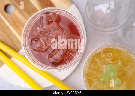 Leckerer Bubble Tee in Plastikbechern und Strohhalmen auf einem hellen Tisch, flach gelegt Stockfoto