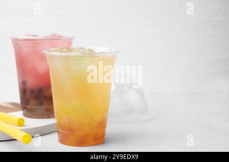 Leckerer Bubble Tee in Plastikbechern und Strohhalmen auf Lichttisch, Platz für Text Stockfoto
