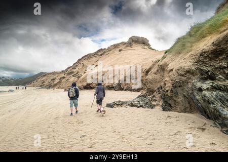 Menschen, die an dem instabilen Sanddünen-System am Crantock Beach in Newquay in Cornwall in Großbritannien vorbeilaufen. Stockfoto