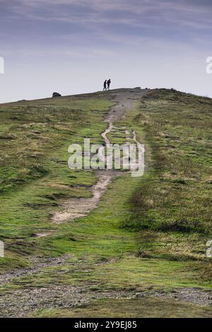 Zwei Figuren, die auf den Überresten einer neolithischen bronzzeitlichen barrow am Ende von Pentire Point East an der Küste von Newquay in Cornwall gehen Stockfoto