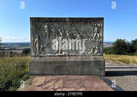 KZ Buchenwald DEU, Deutschland, Weimar, Thüringen, Thüringen, Thüringen, 29.07.2024 Stele mit Szene aus dem Lagerleben zur Zwangsarbeit geschaffen von den Bildhauern Hans Kies , Rene Graetz und Waldemar Grimek an der Gedenkstaette vom ehemaligen Konzentrationslager KZ Buchenwald bei Weimar im Freistaat Thüringen Deutschland . Die heutige nationale Mahn- und Gedenkstaette auf dem einst eines der groessten Konzentrationslager auf deutschem Boden war zwischen 1937 und 1945 auf dem Ettersberg als Haftstaette zur Zwangsarbeit betrieben. Insgesamt waren in diesem Zeitraum etwa Stockfoto