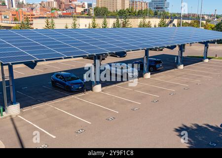 Duluth, MN, USA-15. September 2024: Elektroautos laden auf einem Parkplatz unter Solarpaneelen auf. Stockfoto
