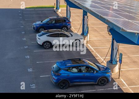 Duluth, MN, USA-15. September 2024: Elektroautos laden auf einem Parkplatz unter Solarpaneelen auf. Stockfoto
