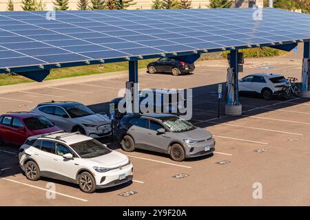 Duluth, MN, USA-15. September 2024: Elektroautos laden auf einem Parkplatz unter Solarpaneelen auf. Stockfoto
