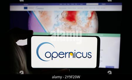 Person, die ein Handy mit dem Logo des ESA-Erdbeobachtungsprojekts Copernicus auf dem Bildschirm vor der Webseite hält. Schwerpunkt auf dem Display des Telefons. Stockfoto