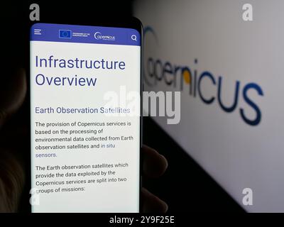 Person, die ein Mobiltelefon hält, mit Webseite des ESA-Erdbeobachtungsprojekts Copernicus auf dem Bildschirm mit Logo. Konzentrieren Sie sich auf die Mitte des Telefondisplays. Stockfoto