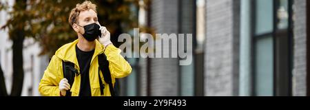 Ein Liefermann in schwarzer Maske trägt an einem geschäftigen Tag einen Befehl zu einem Bürogebäude. Stockfoto