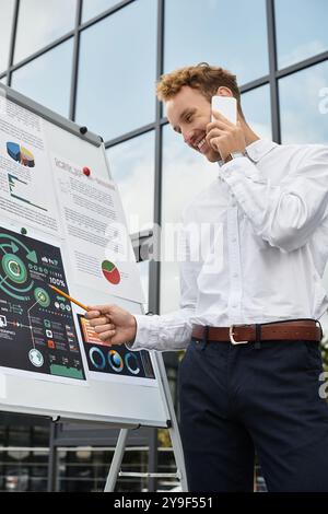 Ein rothaariger Geschäftsmann in einem weißen Hemd nimmt an einer Projektdiskussion Teil, während er in einem Büro steht. Stockfoto