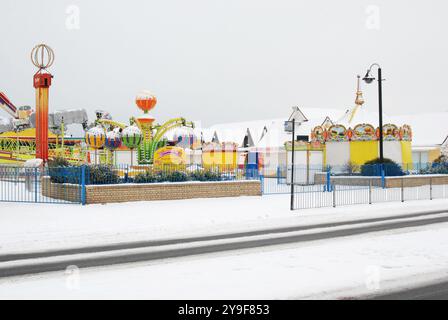 Eine ruhige Winterszene auf einem schneebedeckten Hastings Fairground mit leuchtenden Farben vor der ruhigen, frostigen Kulisse. Stockfoto