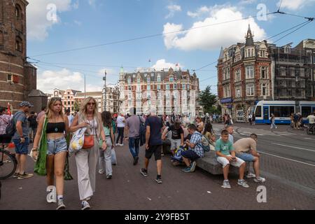 Die Leute laufen auf dem Muntplein mit dem fünf-Sterne-Hotel L'Europe Amsterdam im Hintergrund. Stockfoto