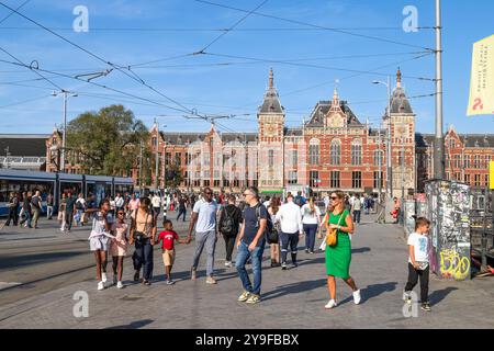 Die Leute laufen über den Vorplatz des Hauptbahnhofs in Amsterdam. Stockfoto