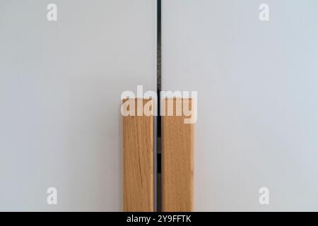 Moderne weiße Schranktüren mit Holzgriff, Möbelhintergrund. Schranktürknöpfe aus Holz Stockfoto