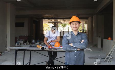 Architekt, Ingenieur, Auftragnehmer oder Bauleiter, der mit einem Armkreuz auf einer Baustelle steht. Stockfoto