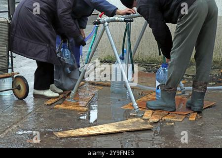 Die Bewohner der Stadt sammeln Trinkwasser aus einem öffentlichen Wasserhahn Stockfoto
