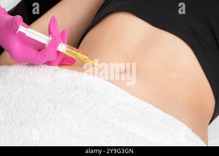 Der Arzt für ästhetische Kosmetologie führt Injektionen gegen Dehnungsstreifen am Bauch und am Körper der Frau durch. Die ästhetische Kosmetik der Frau im Schönheitssalon. Stockfoto