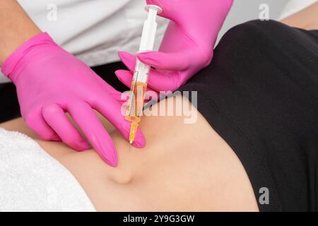 Der Arzt für ästhetische Kosmetologie führt Injektionen gegen Dehnungsstreifen am Bauch und am Körper der Frau durch. Die ästhetische Kosmetik der Frau im Schönheitssalon. Stockfoto