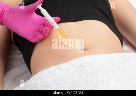 Der Arzt für ästhetische Kosmetologie führt Injektionen gegen Dehnungsstreifen am Bauch und am Körper der Frau durch. Die ästhetische Kosmetik der Frau im Schönheitssalon. Stockfoto