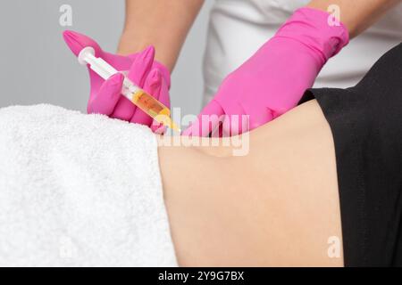 Der Arzt für ästhetische Kosmetologie führt Injektionen gegen Dehnungsstreifen am Bauch und am Körper der Frau durch. Die ästhetische Kosmetik der Frau im Schönheitssalon. Stockfoto