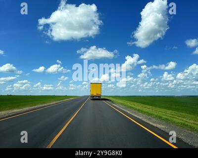 Gelber Lkw auf der Straße. Ein leuchtend gelber Lkw, der auf offener Straße fährt und Transport und Logistik symbolisiert. Stockfoto