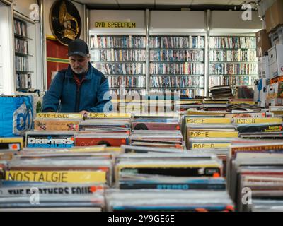 Das Innere des Plattenladens, eine Vielzahl von Schallplatten und cds, ein Mann, der durch die Sammlungen von Schallplatten schaut. Stockfoto