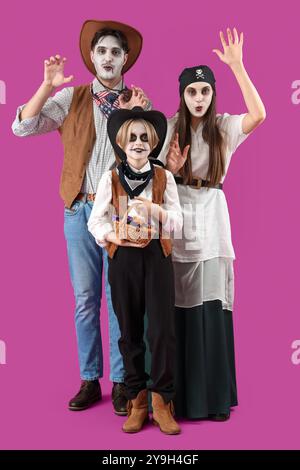 Glückliche Familie, die zu Halloween auf violettem Hintergrund gekleidet ist Stockfoto