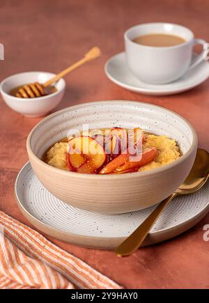 Lebensmittelfotografie von Hirsebrei mit karamelisiertem Pfirsich, Nektarine mit Agavendicksaft, Honig, Tee mit Mandelmilch Stockfoto