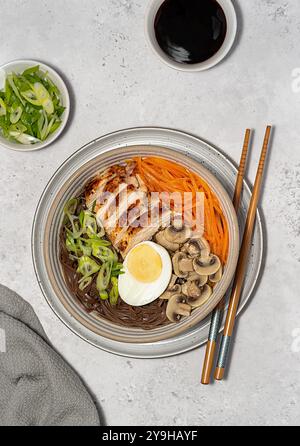 Lebensmittelfotografie von Suppen-Ramen mit Huhn, Soba, Buchweizennudeln, Ei, Pilz, Frühlingszwiebeln und Karotten, Essstäbchen Stockfoto