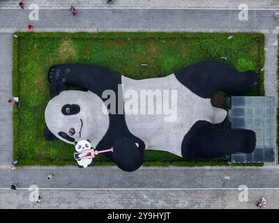 CHENGDU, CHINA - 9. OKTOBER 2024 - Eine 26 Meter lange Skulptur des schwersten Riesenpandas der Welt, mit einem Gewicht von 130 Tonnen, liegt auf dem Boden und hält eine se Stockfoto