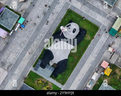 CHENGDU, CHINA - 9. OKTOBER 2024 - Eine 26 Meter lange Skulptur des schwersten Riesenpandas der Welt, mit einem Gewicht von 130 Tonnen, liegt auf dem Boden und hält eine se Stockfoto