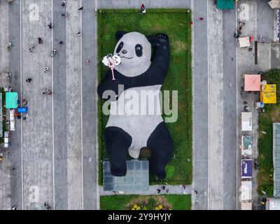 CHENGDU, CHINA - 9. OKTOBER 2024 - Eine 26 Meter lange Skulptur des schwersten Riesenpandas der Welt, mit einem Gewicht von 130 Tonnen, liegt auf dem Boden und hält eine se Stockfoto