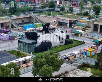 CHENGDU, CHINA - 9. OKTOBER 2024 - Eine 26 Meter lange Skulptur des schwersten Riesenpandas der Welt, mit einem Gewicht von 130 Tonnen, liegt auf dem Boden und hält eine se Stockfoto