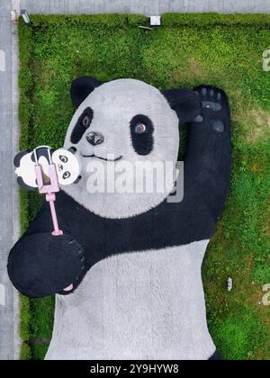 CHENGDU, CHINA - 9. OKTOBER 2024 - Eine 26 Meter lange Skulptur des schwersten Riesenpandas der Welt, mit einem Gewicht von 130 Tonnen, liegt auf dem Boden und hält eine se Stockfoto