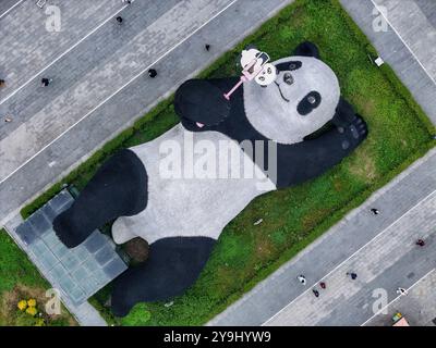 CHENGDU, CHINA - 9. OKTOBER 2024 - Eine 26 Meter lange Skulptur des schwersten Riesenpandas der Welt, mit einem Gewicht von 130 Tonnen, liegt auf dem Boden und hält eine se Stockfoto