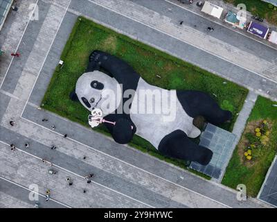 CHENGDU, CHINA - 9. OKTOBER 2024 - Eine 26 Meter lange Skulptur des schwersten Riesenpandas der Welt, mit einem Gewicht von 130 Tonnen, liegt auf dem Boden und hält eine se Stockfoto