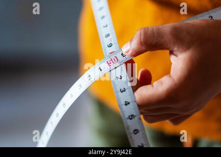 Eine Nahaufnahme einer Hand, die ein Maßband hält und das Maß von 50 Zentimetern zeigt. Der Hintergrund ist verschwommen und konzentriert sich auf das Maßband und Stockfoto