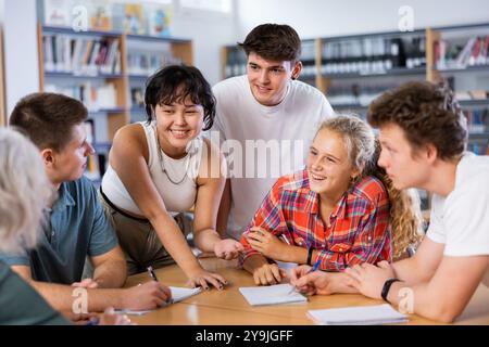 Gruppenporträt lächelnder Jugendkinder, die in der Bibliothek zusammenarbeiten Stockfoto