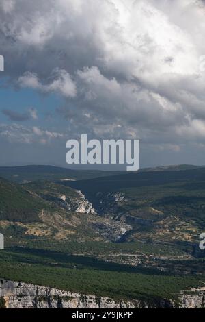 Grüne Klippen und Höhlen der Verdon-Schlucht in Frankreich, mit Sonnenlicht, das die geologischen Formationen und die kontrastierenden Schatten unterstreicht Stockfoto