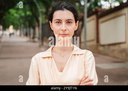 Junge Frau, die nachdenklich in die Kamera blickt, auf einer leeren Straße steht, eine ernste Stimmung und einen kontemplativen Ausdruck in einer urbanen Umgebung widerspiegelt, die auf Nachdenklichkeit und Introspektion hindeutet. Hochwertige Fotos Stockfoto