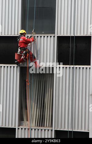 Mexico City, Mexiko; 09 23 2017: Ein Fensterreiniger in der Höhe. Ein Mann, der die Außenfenster eines Gebäudes reinigt. Riskante Jobs. Stockfoto